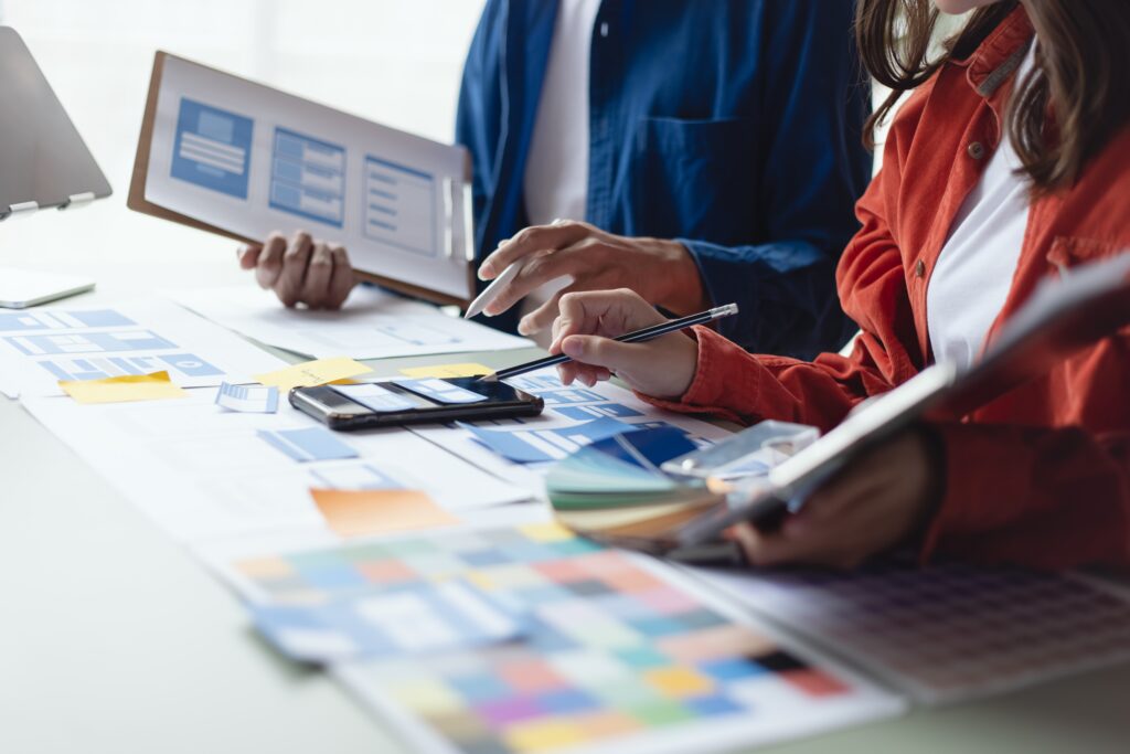 A team working on a brand style guide booklet, color swatches, and logo sketches—representing cohesive brand identity design in progress.