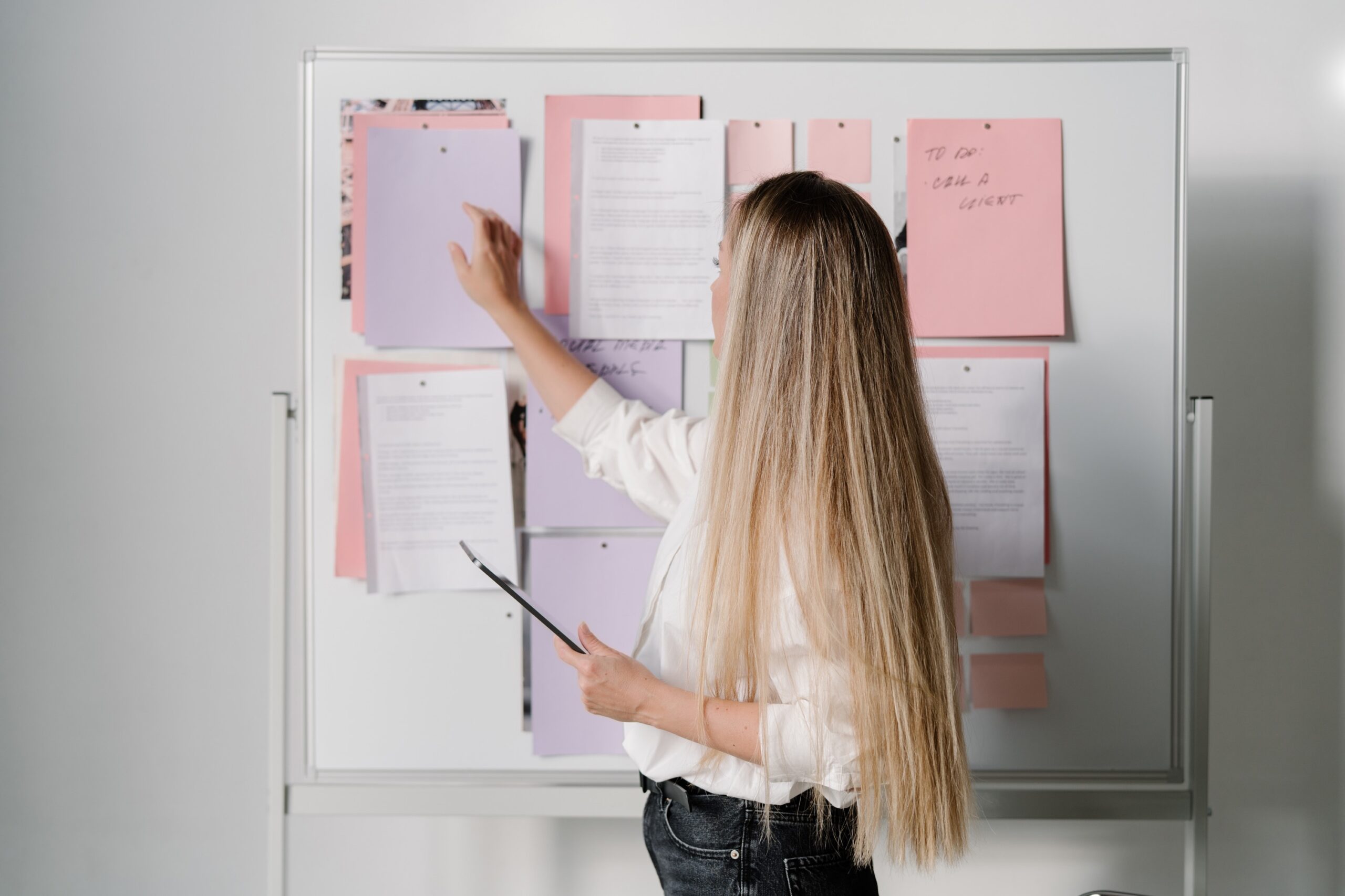 A person in jeans stands beside a flip chart with handwritten strategy notes during a branding or planning session.